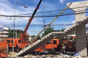 Metropolitan Electricity Authority workers on Monday remove the annoying pole that partially blocked the stairway, built around it, on this new pedestrian overpass in Muang district of Nonthaburi. 